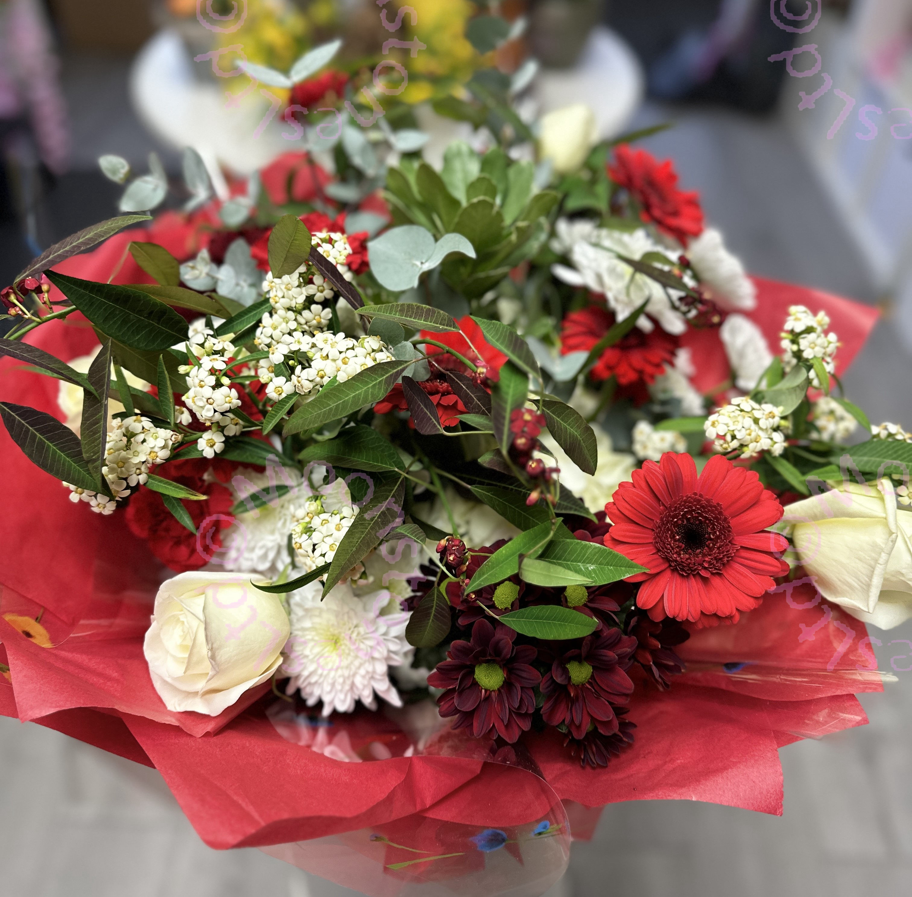 Hand tied bouquet of mixed red and white seasonal flowers. 