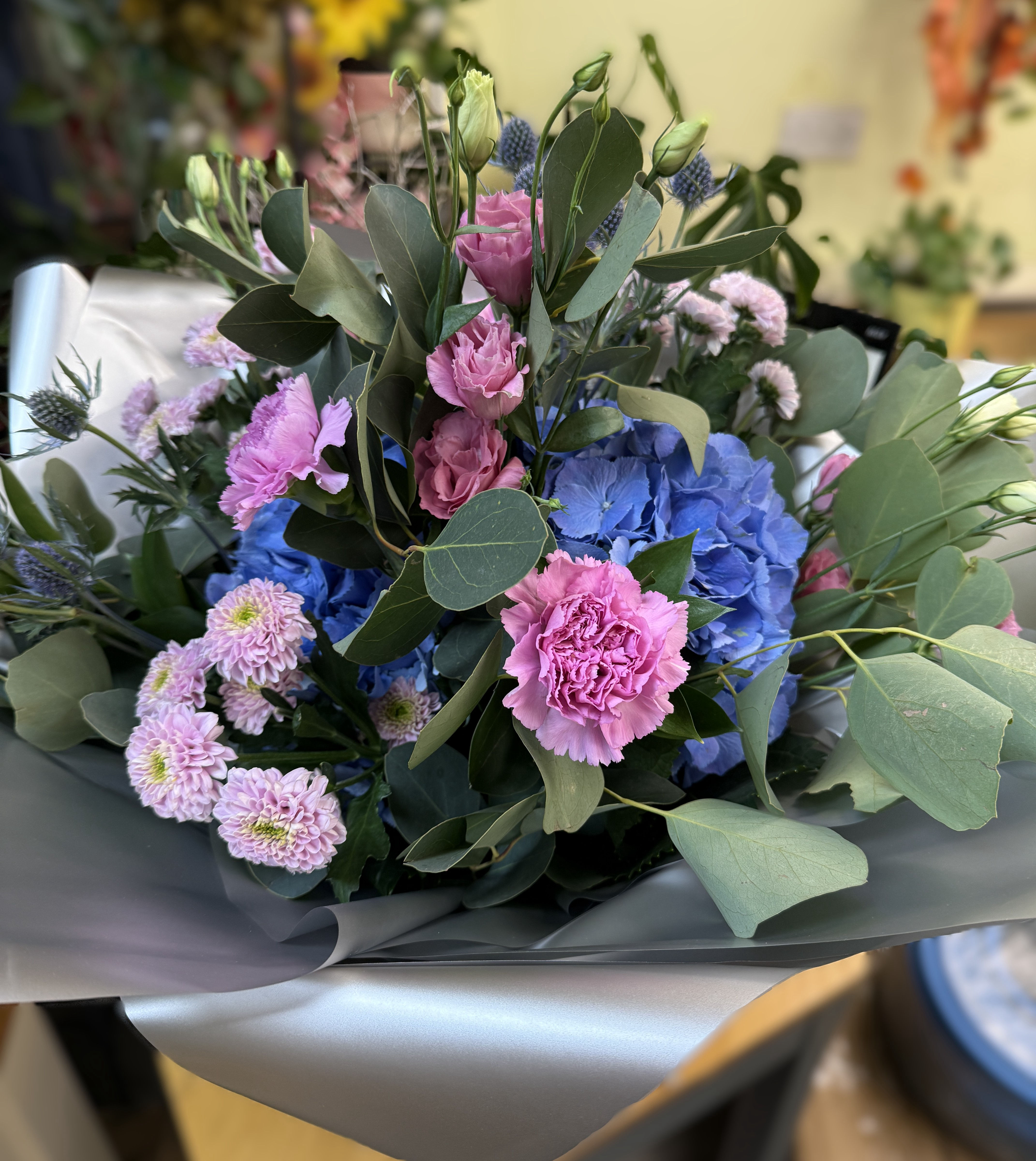 A tied bouquet of mauve, blue and silver flowers and foliages 