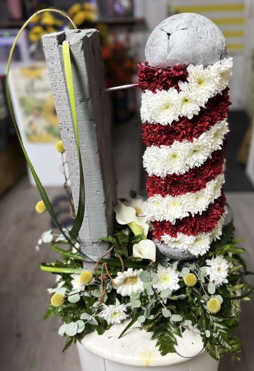 A 3D Barbers Pole created in fresh flowers, attached to a foliage wall. 